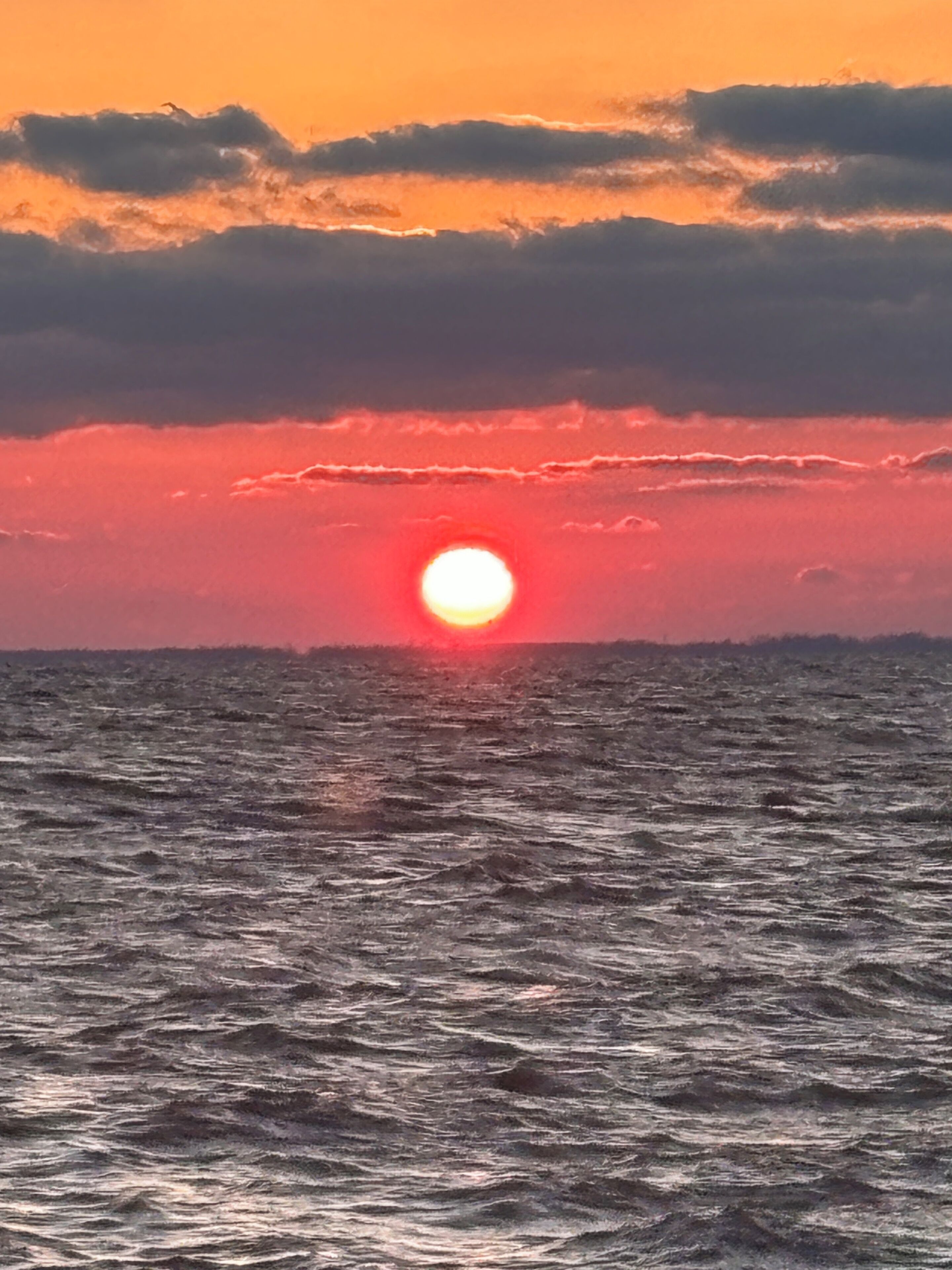 A sunset over the ocean with waves.