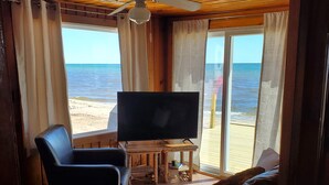 Une pièce avec un plafond en bois, un ventilateur de plafond, une télévision, un canapé et une vue sur la plage.