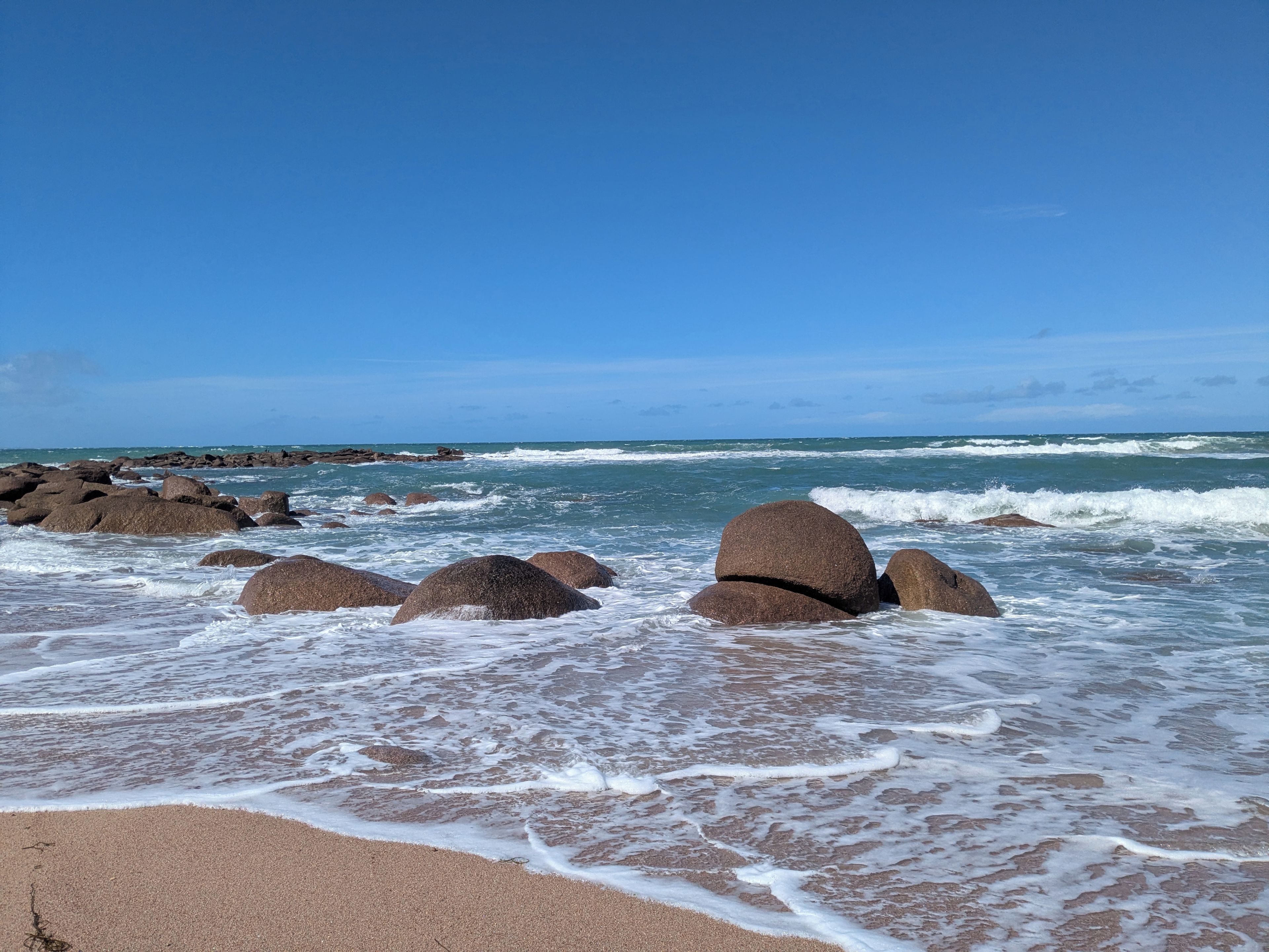 Une plage avec de gros rochers et des vagues.