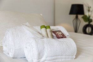 A neatly made bed with a white towel, two bottles of shampoo, and a bar of soap. - L'Aragon - Wifi - Balcon vue La Maine (Angers)