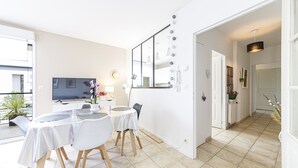 Une chambre d’hôtel moderne dotée d’un coin repas, d’une télévision, d’un miroir avec éclairage intégré et donnant sur le balcon extérieur.
