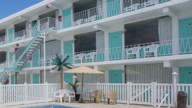 Un hotel de varios pisos con piscina, balcones y zona de estar al aire libre.