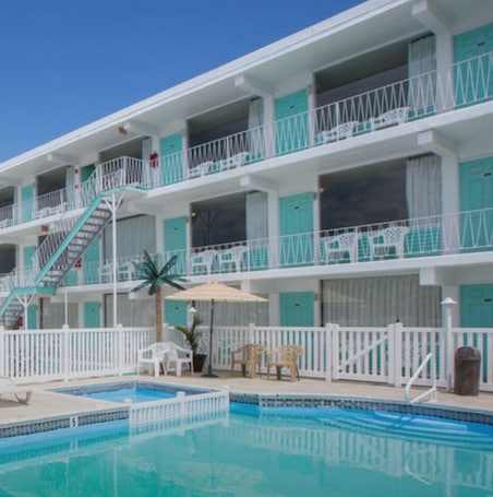 Una piscina al aire libre de temporada, sombrillas. Island Breeze Motel