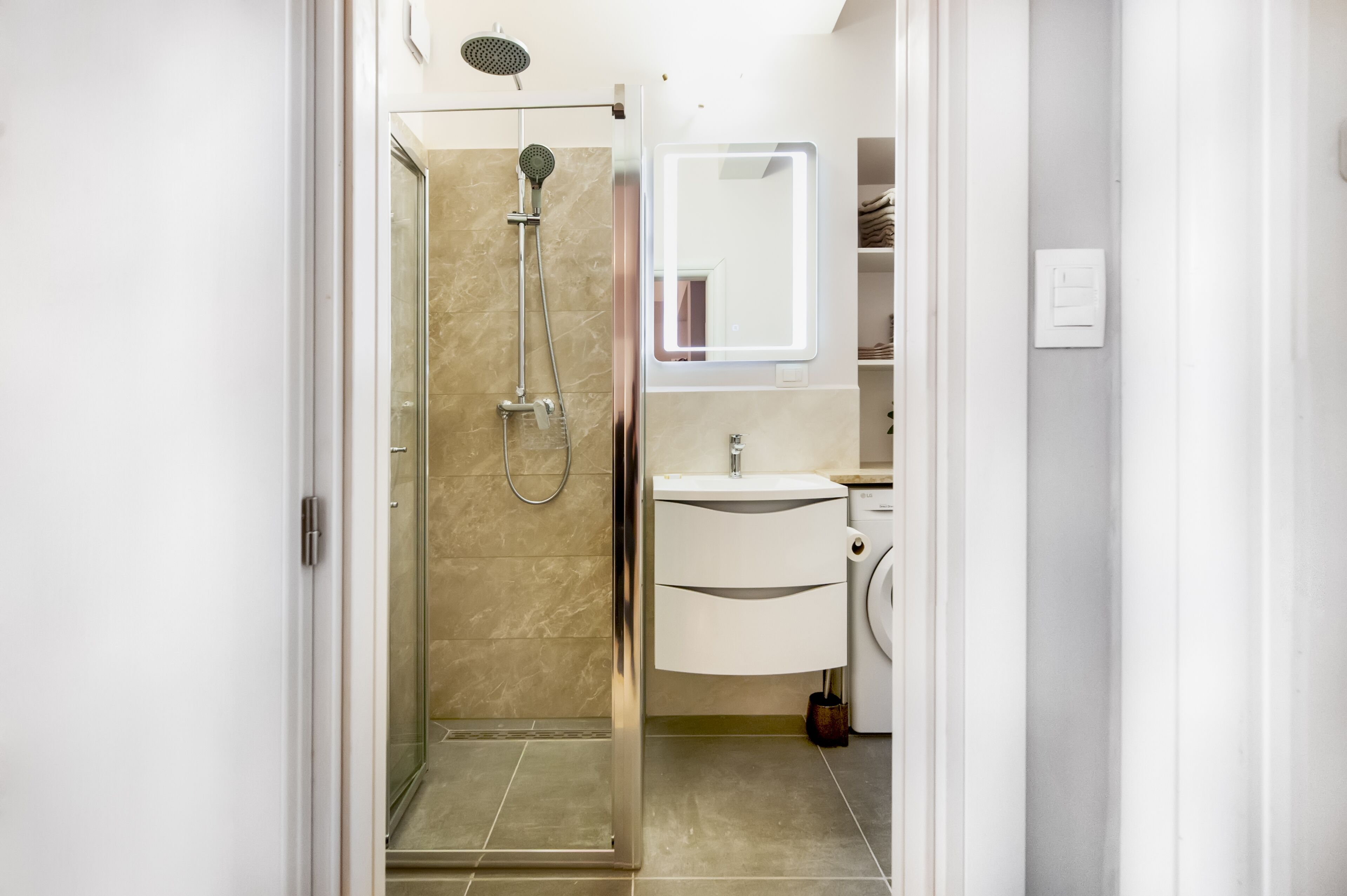 Un baño moderno con cabina de ducha de vidrio, un lavabo blanco y un espejo sobre él.