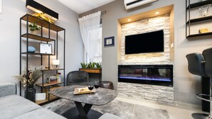 Una sala de estar moderna con chimenea, televisor de pantalla plana y un área de descanso acogedora.
