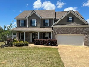 Stunning two-story home with a brick and siding facade, featuring a prominent garage door and a well-manicured lawn.