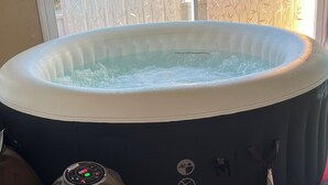 Un bain à remous équipé d’un panneau de commande, d’une pompe à eau et d’une fenêtre agrémentée d’un rideau en bambou.