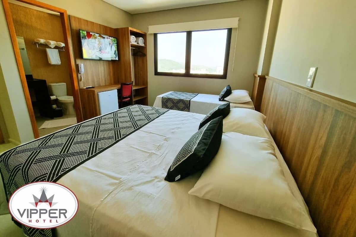 Une chambre d’hôtel avec deux lits, une télévision, une armoire et une fenêtre.