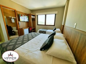 Hotellihuone, jossa on kaksi sänkyä, televisio, vaatekaappi ja ikkuna.