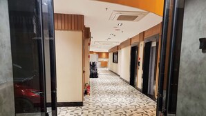 A hotel corridor with a geometric patterned floor, wooden paneling on the walls, and a fire extinguisher on the wall. - VIPPER Hotel (Aparecida)