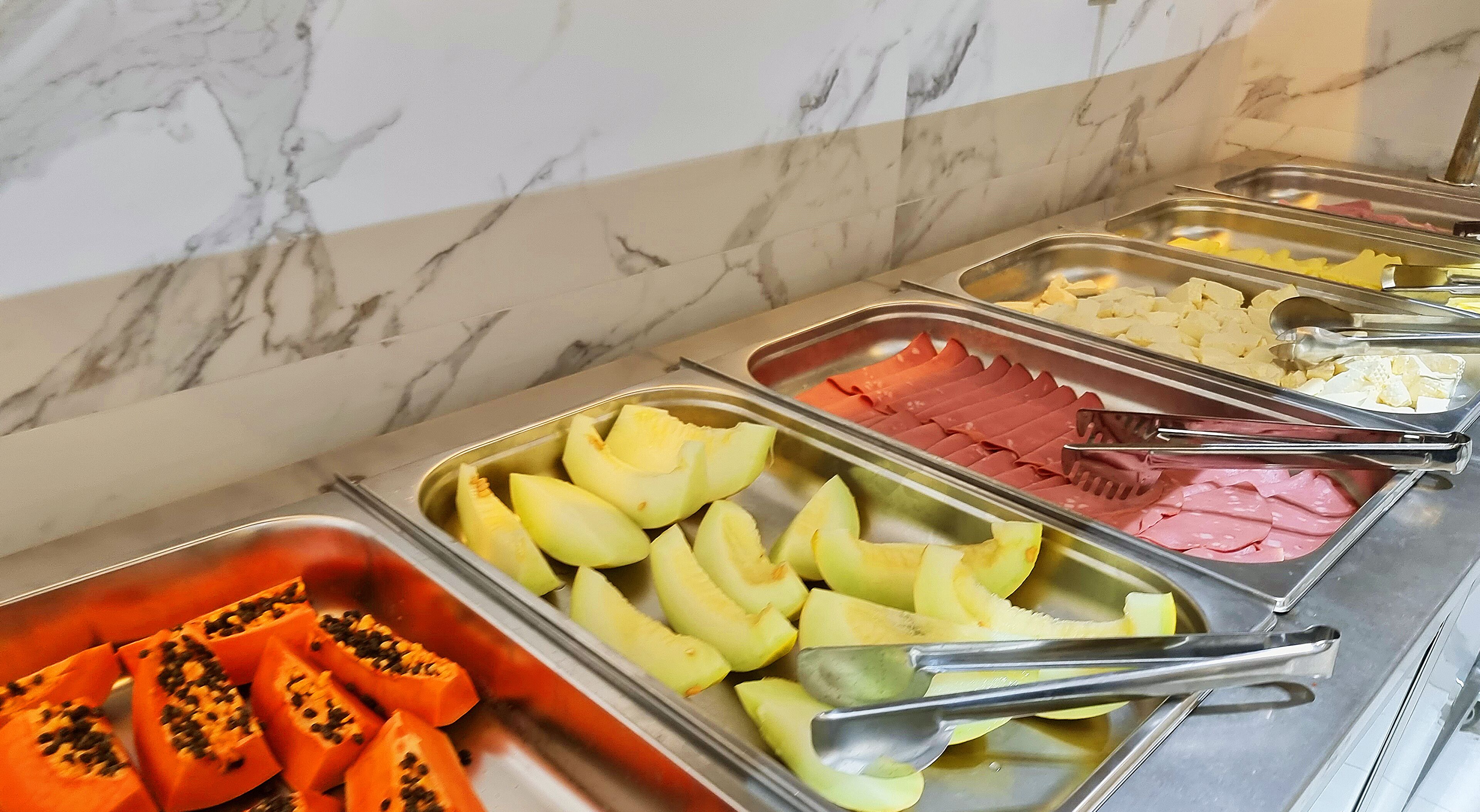 Een buffet met diverse gerechten, waaronder fruit en vlees.