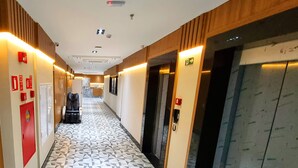 A hotel corridor with patterned flooring, emergency equipment, and an elevator. - VIPPER Hotel (Aparecida)