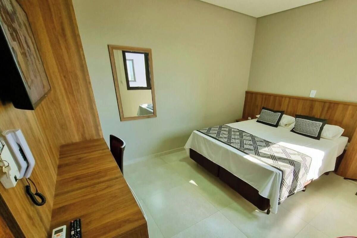 Une chambre à coucher comprenant un lit, une table de chevet, un miroir et un téléphone.