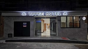 The exterior of the Vipper Hotel with a modern facade, a glass entrance, and a visible fire extinguisher. - VIPPER Hotel (Aparecida)