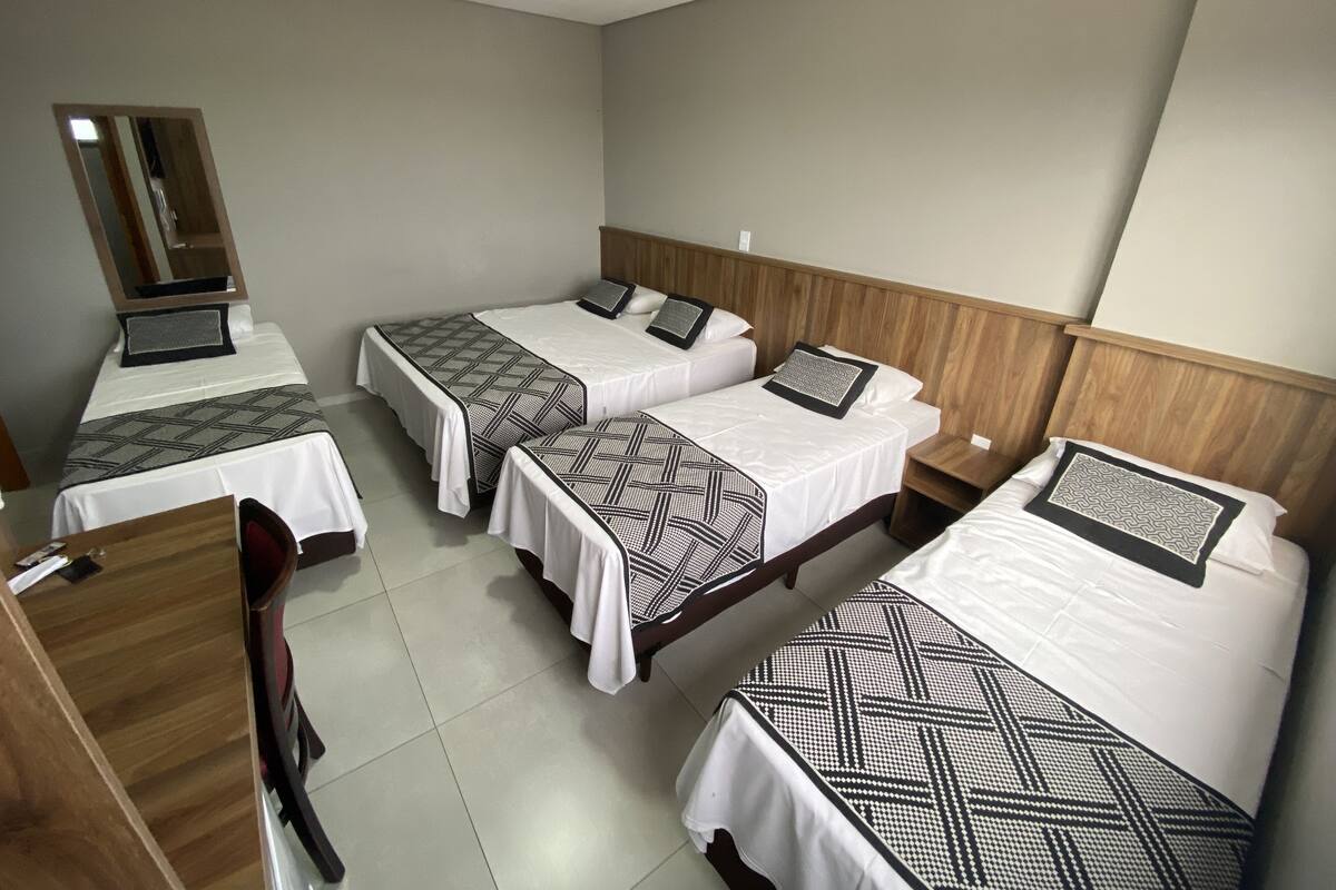 Une chambre d’hôtel avec trois lits, un bureau et une chaise.