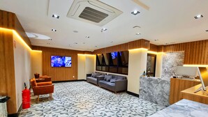 A modern hotel room with a patterned floor, a sofa, a TV, and a desk with a lamp. - VIPPER Hotel (Aparecida)