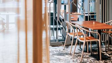 A modern interior with a wooden table and chairs, a patterned floor, and a view through a glass partition.