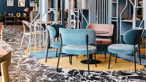 A modern interior with a curved bookshelf, seating area, and a marble-patterned floor. - Mercure Brest Centre Port (Brest)