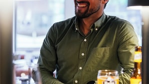 A person standing at a bar counter with a glass of beer and a bottle of beer in the background. - Mercure Brest Centre Port (Brest)