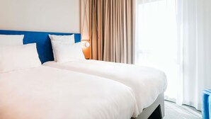 A hotel room with two beds, a blue headboard, a large window with curtains, and a wall-mounted lamp. - Mercure Brest Centre Port (Brest)