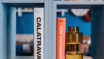 Dos libros titulados 'CALATRAVA' y 'FOTOGRAFÍA SURF' de LEROY GRANNIS, sobre una estantería junto a un frasco de perfume.