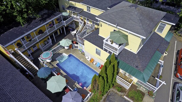 A multi-story building with a swimming pool, outdoor seating, and a covered patio area. - Beach Motel & Suites (Old Orchard Beach)