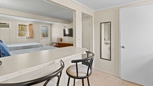 A compact room with a kitchenette, a bed, a TV, and a door. - Beach Motel & Suites (Old Orchard Beach)