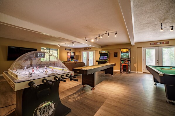 A room with a foosball table, pool table, and arcade games. - Heated Private pool, spacious gameroom with five king bedrooms. (Gatlinburg)