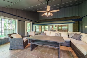 A spacious patio with wicker furniture, a ceiling fan, and large windows offering views of the outdoors. - Heated Private pool, spacious gameroom with five king bedrooms. (Gatlinburg)