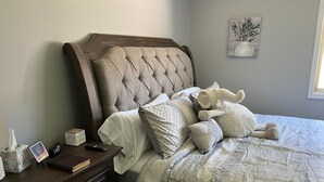 Une chambre à coucher avec une tête de lit en bois, une table de chevet sur laquelle se trouvent un livre, une boîte de mouchoirs et une télécommande.