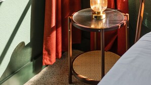 A balcony with red curtains, a wicker chair with a lamp, and a view of palm trees. - 114 · Pool Beach Self Checkin Free Parking (Clearwater)