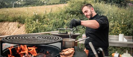 Une personne qui cuisine en plein air à l’aide d’un réchaud portable et de casseroles.