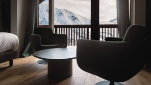 Una habitación de hotel moderna con un ventanal grande, una mesa redonda, dos sillas y una cama.