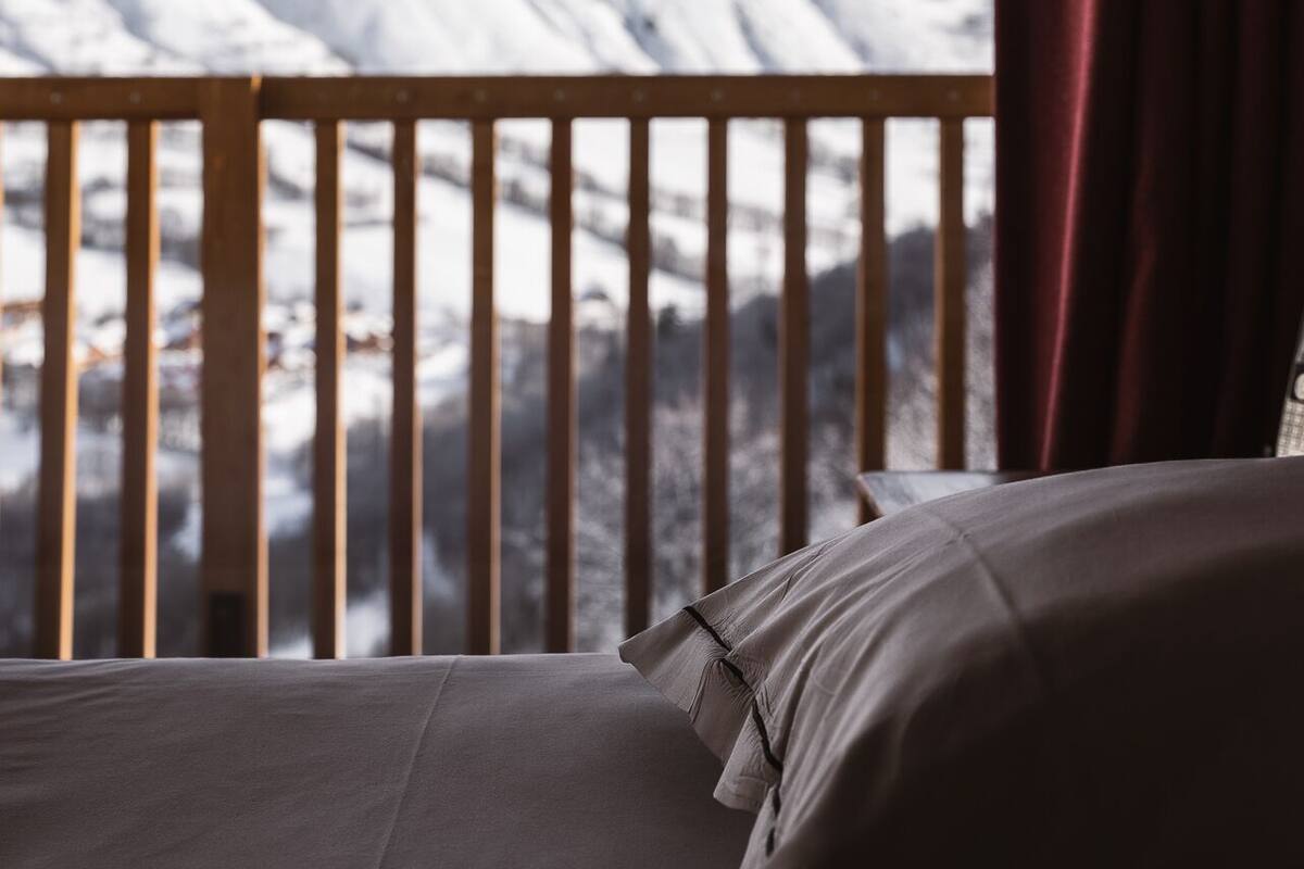 Una cama con vistas a montañas nevadas.