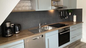 A modern kitchen with a dishwasher, stove, sink, and a coffee maker. - Vacation cottage by the lake (Möhnesee)