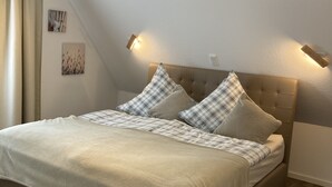 A bedroom with a bed, a headboard, and wall-mounted lighting. - Vacation cottage by the lake (Möhnesee)