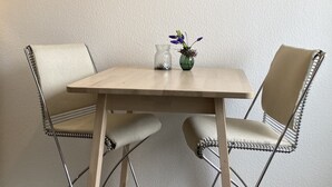 A dining area with a table and two chairs, a vase with flowers, and a painting of Highland cattle on the wall. - Vacation cottage by the lake (Möhnesee)