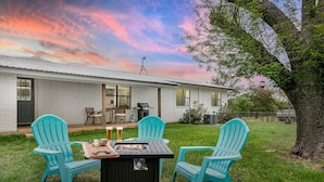 A house with a patio area featuring a grill and two turquoise chairs.