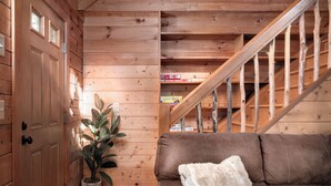 A wooden interior with a brown leather sofa, a white throw pillow, and a potted plant. - Shenandoah Log Cabin *Hot Tub* *Indoor Fireplace* (Dyke)