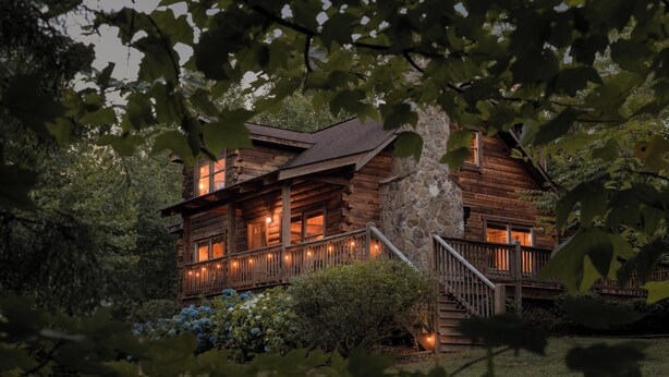 A log cabin with a stone foundation, wooden exterior, and a porch with lights. - Shenandoah Log Cabin *Hot Tub* *Indoor Fireplace* (Dyke)