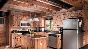 A wooden cabin-style kitchen with a central island, stainless steel appliances, and a large window. - Shenandoah Log Cabin *Hot Tub* *Indoor Fireplace* (Dyke)