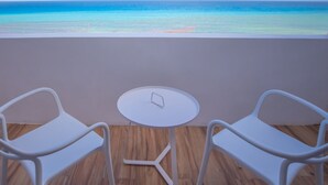 A balcony with two white chairs and a small round table, overlooking a turquoise sea and clear sky. - Brisas Beachfront Penthouses (Cancun)