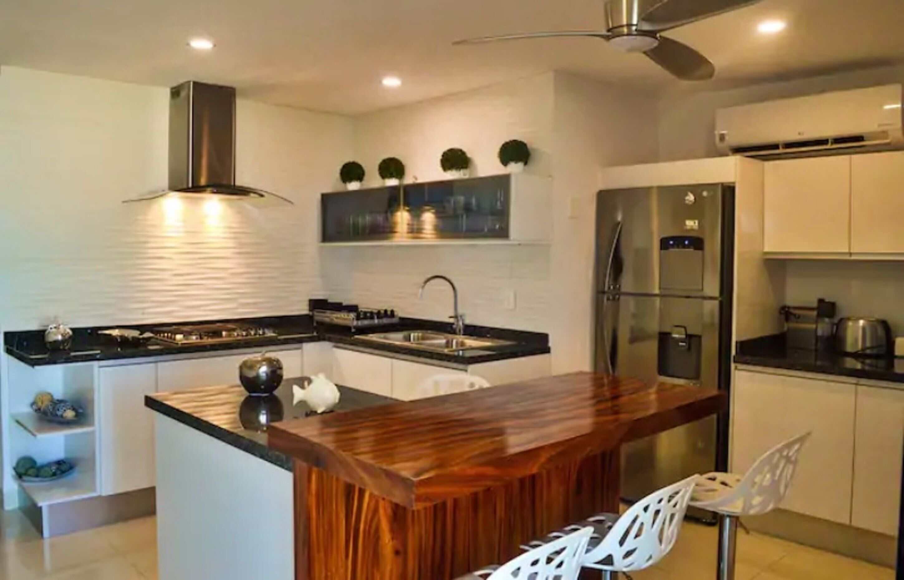 A modern kitchen with a central island, stainless steel appliances, and white cabinetry.