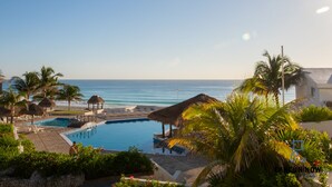 A resort with a swimming pool, beach umbrellas, and palm trees. - Brisas Beachfront Penthouses (Cancun)