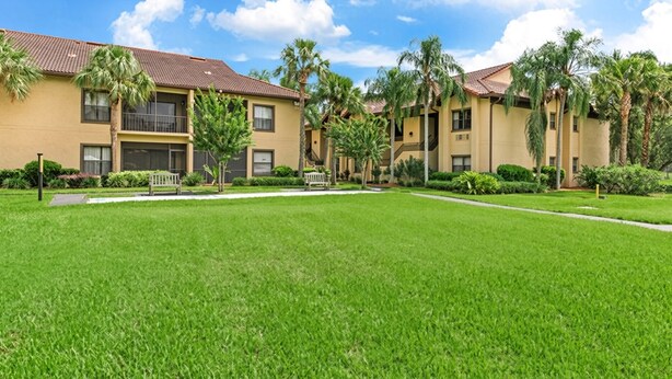 A residential building with a flat roof, multiple balconies, and a well-maintained lawn.