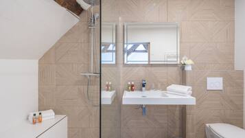 A modern bathroom with a shower, sink, and toilet.