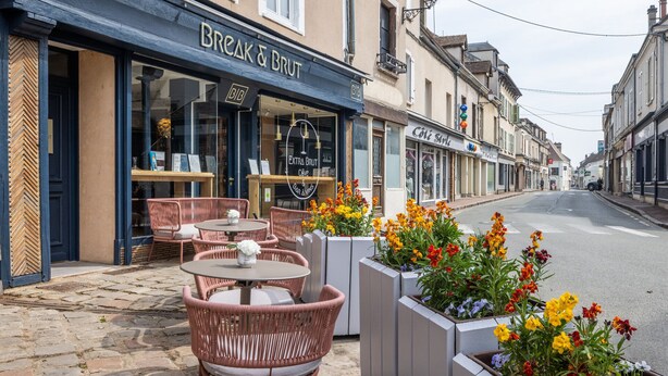 An outdoor seating area with wicker chairs and tables, a café named 'Break & Brut', and flower planters along the sidewalk. - Break & Brut (Nogent-le-Roi)