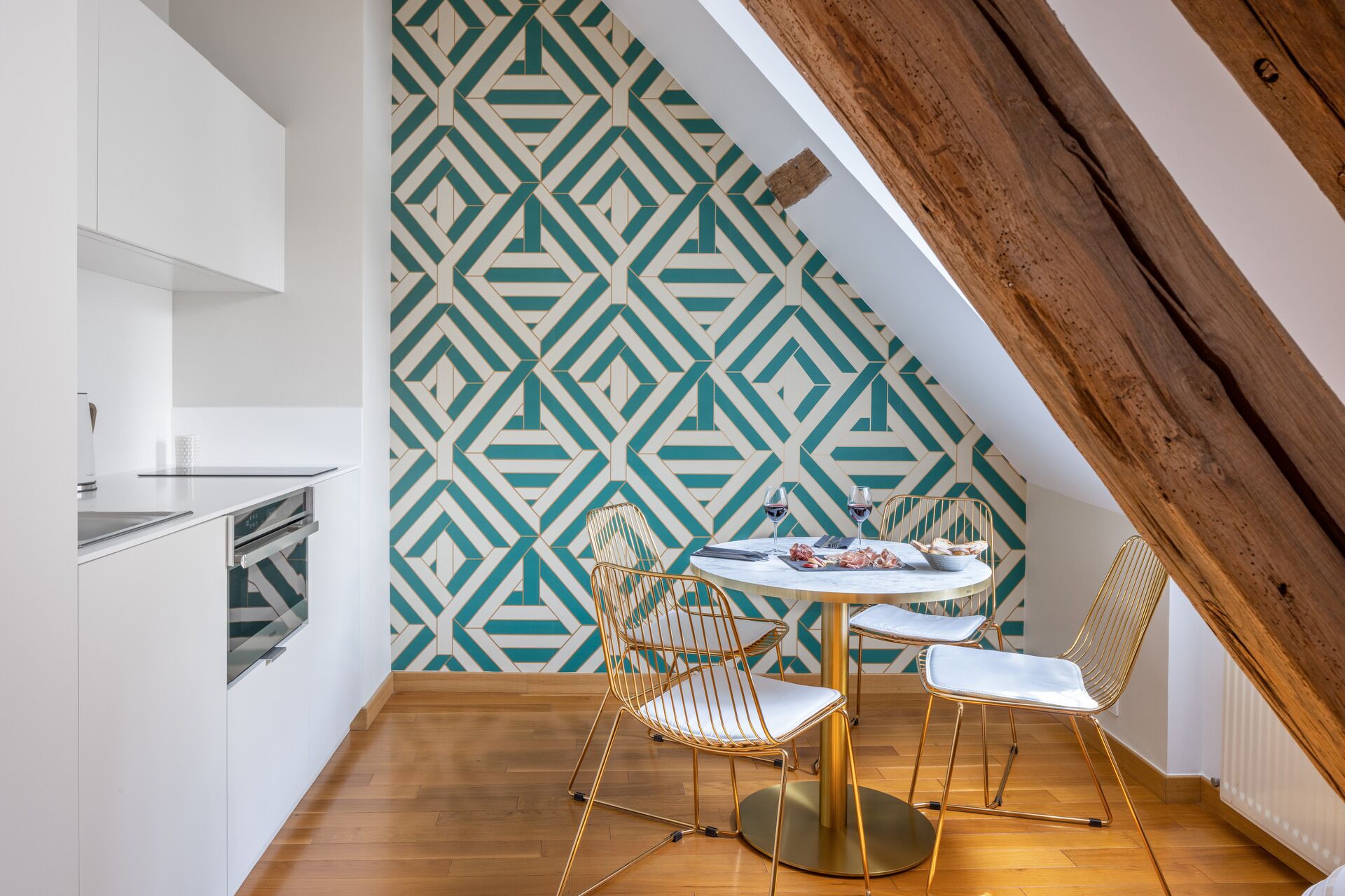 A dining area with a geometric patterned wall, a round table, and two chairs.