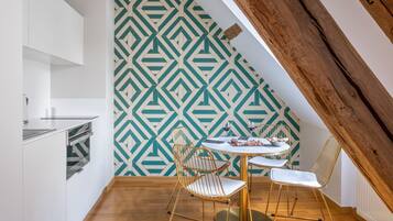 A dining area with a geometric patterned wall, a round table, and two chairs.