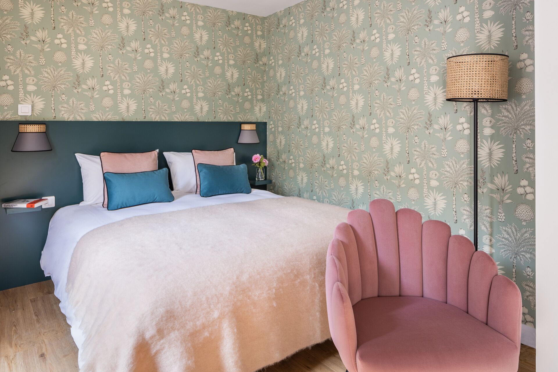 A bedroom with a bed, pillows, a bedside table with a lamp, a chair, and a floor lamp.